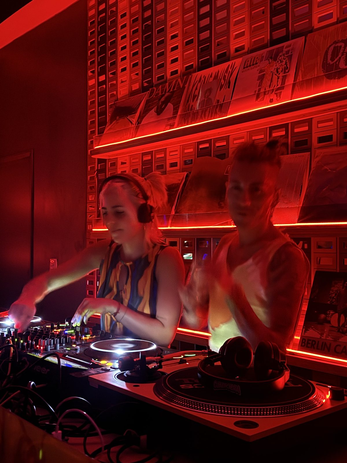 Cabina de DJ con vinilos y luz roja en OYE